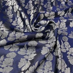 a blue and white floral print fabric with silver flowers on it's side,