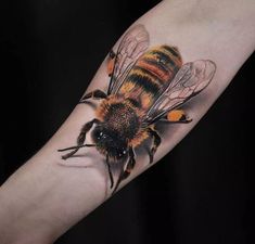 a close up of a person's arm with a tattoo on it and a bee