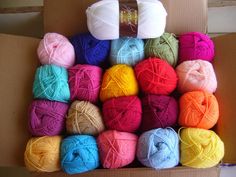 a box filled with balls of yarn in different colors and sizes on top of each other