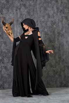 a woman dressed in black holding a horned mask