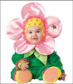 a baby wearing a pink flower and green outfit with yellow dots on it's head