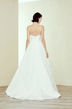 a woman in a white wedding dress standing on a wooden floor with her back to the camera