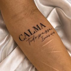 a close up of a person's arm with a tattoo saying calma on it