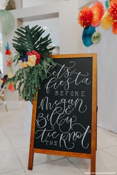 a sign that is sitting on the floor in front of some flowers and balloons with decorations around it