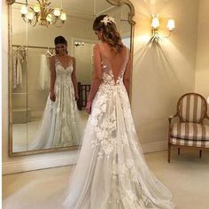 a woman standing in front of a mirror wearing a wedding dress with flowers on it