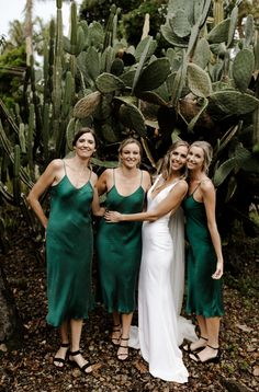 three women in green dresses standing next to each other near cacti and cactus trees