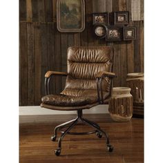 a brown leather office chair sitting in front of a wooden wall with pictures on it