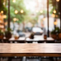 an empty wooden table in front of a window with cars parked on the street behind it