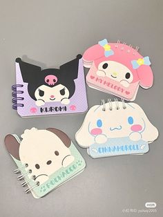 three notebooks with cartoon characters on them sitting next to each other in front of a gray background