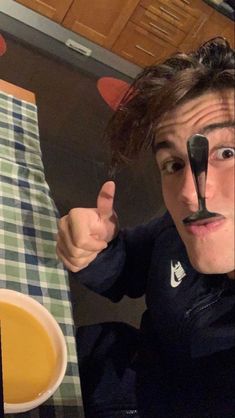 a man with a fake nose and mustache sitting at a table in front of a bowl of soup