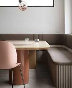 a table with two pink chairs next to it and a bench in front of the window