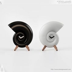 two clocks sitting next to each other on top of wooden legs with black and white faces