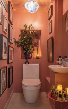 a bathroom with pink walls and pictures hanging on the wall, including a white toilet