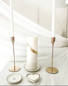 three candles are sitting on top of each other in front of a white cloth covered wall