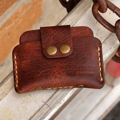 a brown leather wallet sitting on top of a wooden bench next to a metal chain