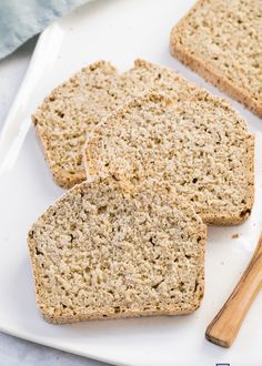 three slices of bread on a white plate next to a wooden spoon and napkins