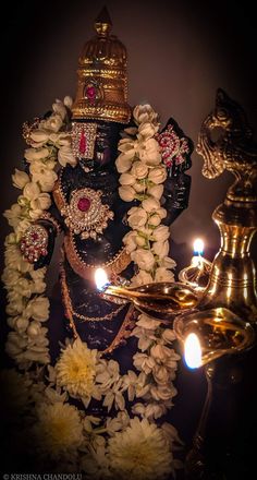 an idol is surrounded by flowers and candles in front of a lamp on a dark background