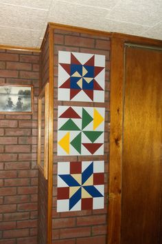 a wall hanging on the side of a brick building next to a wooden door and window