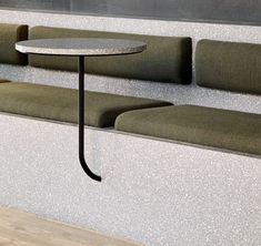 a table sitting on top of a wooden floor next to a wall filled with green couches