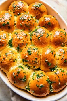 a casserole dish filled with hot cross buns covered in cheese and parsley