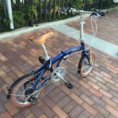 a blue bike parked on top of a brick sidewalk