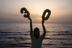 a woman holding up two large balloons in the air with the number 30 written on them