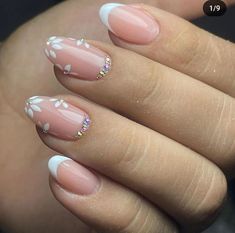 a woman's hand with some pink and white nail polish on her nails,