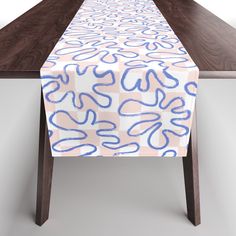 a table with a blue and pink design on it, sitting next to a wooden table