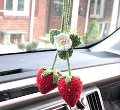 two crocheted strawberries hanging from a car dash board