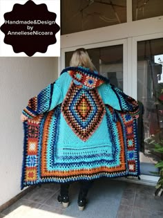 a woman is standing in front of a door with a crocheted blanket on her back