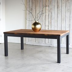 a wooden table with a metal vase on top