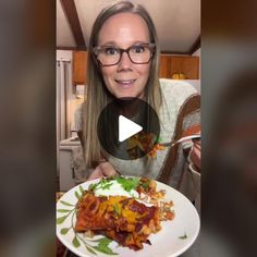 a woman is holding a plate with food on it and smiling at the camera while wearing glasses