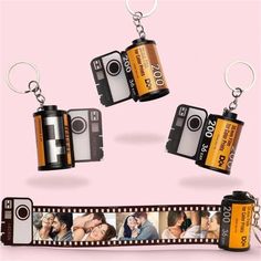 two camera keychains are attached to a film strip with pictures on it and one is holding a couple's face