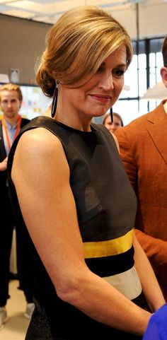 a woman in a black and yellow dress cutting a cake