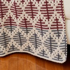 a crocheted blanket sitting on top of a wooden floor next to a white couch