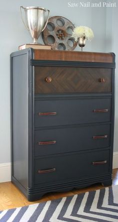 the dresser is painted gray and has gold accents on it, along with a silver vase