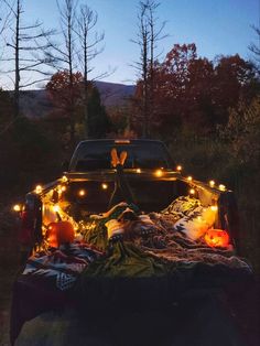 a pick up truck with lights on it parked in the woods next to trees and pumpkins