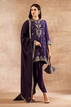 Purple straight tunic with contrast zardozi embroidery in a floral pattern. Comes with embroidered dupatta and dhoti pants.
Component: 3
Pattern: Embroidery
Type Of Work: Zardozi
Neckline: Round
Sleeve Type: Three Quarter
Fabric: Silk
Color: Purple
Other Details: 
Keyhole cutout with loop button
Side slits
Loop trim at the neckline
Scalloped border with embroidery
Note: Potli bag carried by the model is not for sale
Occasion: Wedding - Aza Fashions Luxury Purple Unstitched Suit With Traditional Drape, Purple Unstitched Embroidered Silk Suit, Purple Kurta With Intricate Embroidery And Traditional Drape, Semi-stitched Purple Palazzo Set With Intricate Embroidery, Semi-stitched Purple Kurta With Intricate Embroidery, Bridal Lehenga Designs, Jayanti Reddy, Dhoti Pants, Embroidered Tunic