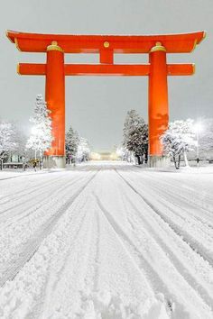 a large red gate in the middle of a snow covered field