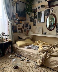 an unmade bed sitting in a bedroom next to a window with pictures on the wall