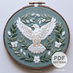 an embroidered white bird with green leaves and flowers