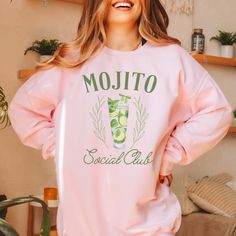 Hey Mojito enthusiast, are you ready to bring the vibrant energy of a tropical getaway into your everyday style? Introducing our "Mojito Social Club" Sweatshirt, the perfect blend of relaxation and fun! This sweatshirt offers softness and comfort. The Mojito-inspired graphic adds a refreshing twist to your wardrobe, instantly transporting you to a beachside paradise with its playful vibes. Whether you're hosting a backyard barbecue with friends or lounging by the pool with a good book, our sweatshirt is your go-to choice for effortless style. Its relaxed fit ensures you stay comfortable and cool, no matter how hot the day gets. From day-drinks with the girls to sunset strolls along the boardwalk, this sweatshirt is as versatile as it is stylish. Pair it with your favorite denim shorts for Social Club Design, Mojito Glass, Club Sweatshirts, Fresh Mint Leaves, Backyard Barbecue, Vibrant Energy, Club Design, Mint Leaves, Fresh Mint