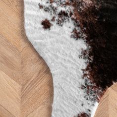 an area rug with brown and white fur on it's side, next to a wooden floor