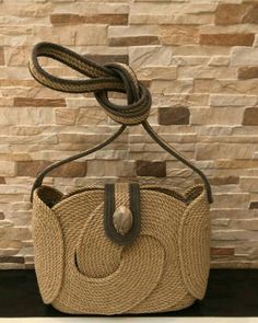 a straw bag with rope hanging from it's handle on a shelf in front of a stone wall