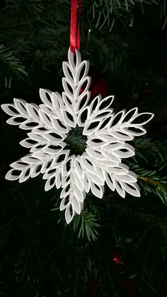 a white snowflake ornament hanging from a christmas tree