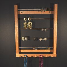 a wooden display case holding several pairs of rings and earring hooks with beads hanging from the sides