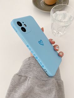 a person holding a blue phone case on top of a white table next to an egg