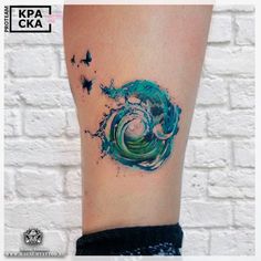 a woman's leg with a green and blue wave tattoo on it