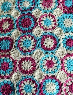 a crocheted blanket is shown with pink, blue and white circles on it