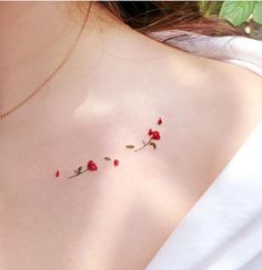 a woman's chest with three small red roses attached to the back of her shoulder